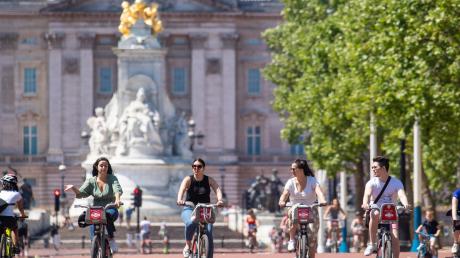 Radfahrer genießen vor dem Buckingham Palace in London das sommerliche Wetter. Sechs Menschen dürfen sich im Freien wieder treffen. 