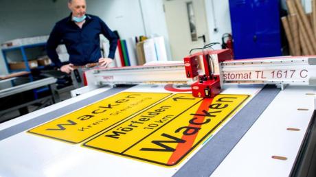 Michael Mazur, Abteilungsleiter Druckverfahren in der Fritz Lange GmbH, begutachtet den Zuschnitt einer Ortstafel von Wacken auf spezieller selbstklebender Folie.