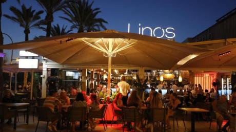 Menschen sitzen in einer Bar an der Strandpromenade von Palma.