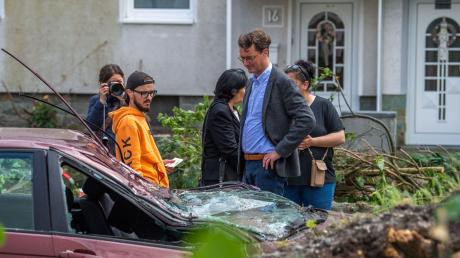 Hendrik Wüst (CDU, 2.v.r.), Ministerpräsident von Nordrhein Westfalen, spricht in Lippstadt mit einem Anwohner, dessen Auto durch den Sturm zerstört wurde.