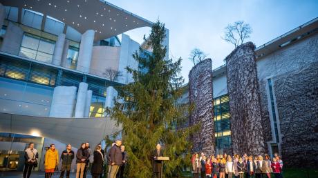 Bundeskanzler Olaf Scholz (Mitte) steht vor der "Kanzlertanne" in Berlin. Die Weihnachtsbeleuchtung brennt zwar nur wenige Stunden am Tag. Beim eigenen Personal ist die Regierung weniger sparsam.