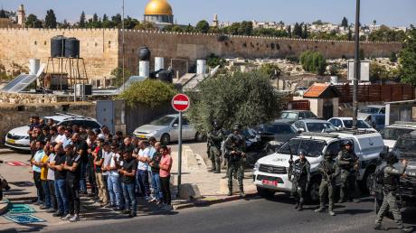Palästinensische Gläubige beten außerhalb der Altstadt von Jerusalem, während israelische Streitkräfte Wache stehen.
