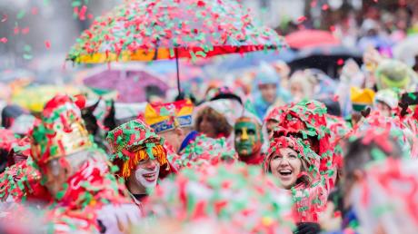 Karnevalisten sind komplett mit nassem Konfetti bedeckt und feiern die Eröffnung des Straßenkarnevals in Köln.