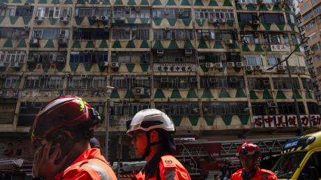Im Hintergrund ist das ausgebrannte Hochhaus in Hongkong zu sehen - bei der Feuerwehr waren zahlreiche Hilferufe eingegangen.