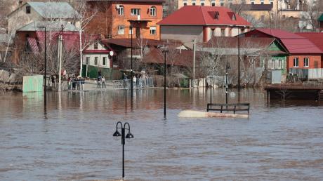 Anwohner stehen an einer Absperrung und beobachten ein überschwemmtes Gebiet im russischen Orenburg.