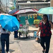 In Thailands Hauptstadt Bangkok schützen sich Menschen mit Schirmen vor der extremen Hitze. 