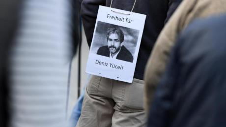 Ein Mann hat sich am 13. April während einer Mahnwache in Hessen ein Transparent mit der Aufschrift «Freiheit für Deniz Yücel!» und dem Porträt des in der Türkei inhaftierten deutsch-türkischen Journalisten umgehängt.