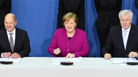 „Wir können auch gerne freundlich gucken“: Bundeskanzlerin Angela Merkel (CDU) unterzeichnet gemeinsam mit dem kommissarischen SPD-Chef Olaf Scholz (links) und dem CSU-Vorsitzenden Horst Seehofer den Koalitionsvertrag – 169 Tage nach der Bundestagswahl.  	