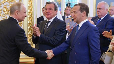 Der alte und sicherlich neue russische Ministerpräsident Medwedew gratuliert dem alten und neuen Präsidenten Putin nach dem Amtseid. Dazu klatscht Ex-Bundeskanzler Gerhard Schröder.