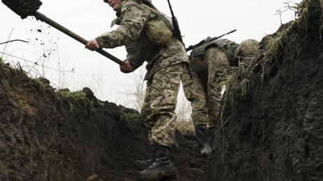 Ukrainische Soldaten heben nahe der Front bei Mariupol Gräben aus.  