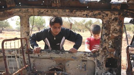 Kinder spielen nahe der Stadt Idlib an einem zerstörten Auto. Noch immer findet der Krieg in Syrien kein Ende. 