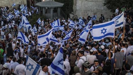 Menschen schwenken israelische Fahnen bei dem umstrittenen Flaggenmarsch in Jerusalem, der von rechtsgerichteten Nationalisten in Israel organisiert worden ist. Tausende Nationalisten zogen bei dem Marsch durch die Stadt.