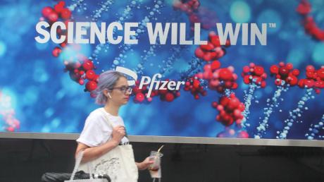 Eine Frau geht in New York an einem Werbeplakat des Unternehmens Pfizer vorbei. Der Impfstoff von Biontech-Pfizer ist jetzt vollständig zugelassen.   