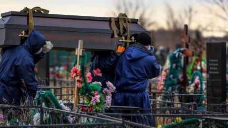 Totengräber tragen auf einem Friedhof in Omsk einen Sarg mit dem Leichnam eines Patienten, der am Coronavirus gestorben ist.