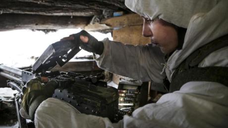 Ein ukrainischer Soldat in den umkämpften Gebieten im Osten des Landes überprüft ein Maschinengewehr.