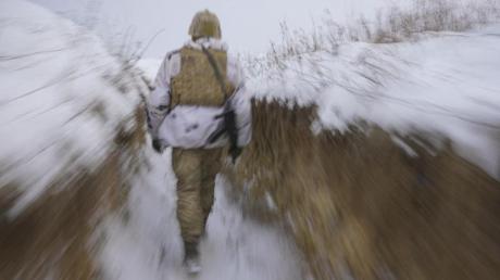 Ein ukrainischer Soldat geht an der Frontlinie durch einen Graben.