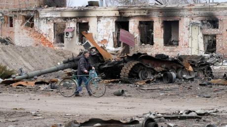 Ein Anwohner geht mit seinem Fahrrad in Trostjanez rund 400 km östlich von Kiew vor beschädigten Gebäuden und einem zerstörten Panzer entlang.