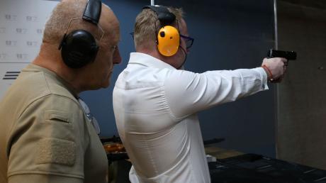 Unter den wachsamen Augen von Schießtrainer Krzysztof Przepiorka übt Unternehmensberater Piotr Piela mit der Pistole auf einem Schießstand.