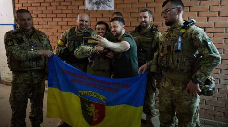 Der ukrainische Präsident Wolodymyr Selenskyj (M) besucht Soldaten an der Front.