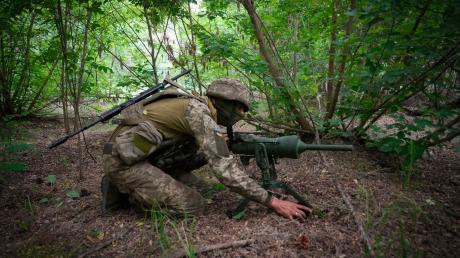 Ein Soldat einer ukrainischen Spezialeinheit legt eine von Deutschland gespendete DM22-Panzerabwehrmine auf einem Waldweg aus.