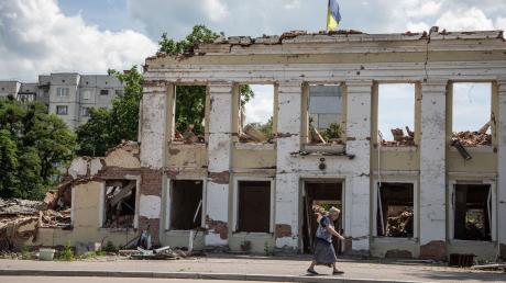 Eine Frau geht an den Ruinen der Stadtverwaltung von Ochtyrka vorbei.