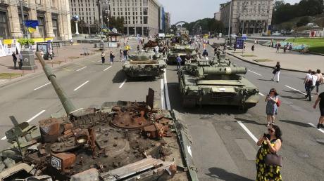 Menschen besuchen das Zentrum von Kiew, wo zerstörte russische Panzer ausgestellt sind.