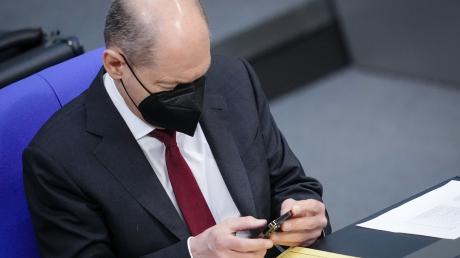 Bundeskanzler Olaf Scholz schaut im Bundestag auf sein Handy (Archivbild).