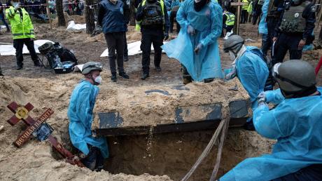 Ukrainische Rettungskräfte bergen bei der Exhumierung in Isjum einen Sarg.