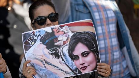 Eine Iranerin beteiligt sich in Frankfurt an einer Demonstration gegen das politische Regime im Iran. Dabei hält sie ein Plakat mit dem Bild der 22-jährigen  Mahsa Amini in den Händen.