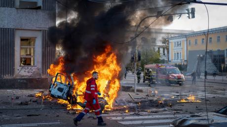 Ein Sanitäter geht nach einem russischen Angriff auf Kiew an einem brennenden Auto vorbei.