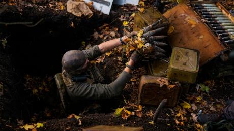 Ein Mitglied der ukrainischen Streitkräfte nimmt in Hrakove zurückgelassene russische Munition auf.