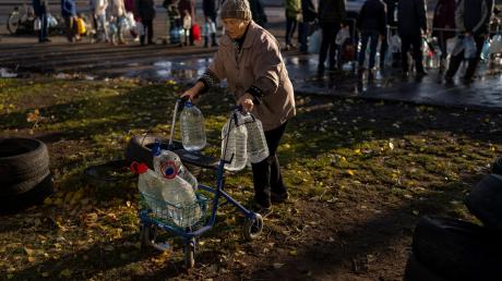 Eine ältere Frau hat in Mykolajiw in der Südukraine ihren Rollator mit Plastikflaschen beladen.