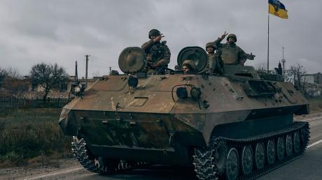 Ukrainische Soldaten zeigen ein Victory-Zeichen während sie mit einem erbeuteten russischen Schützenpanzer fahren.