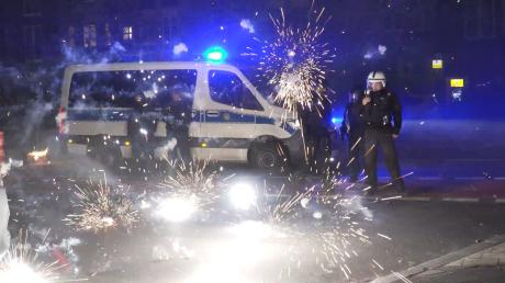 Polizeibeamte stehen in der Neujahrsnacht in Berlin hinter explodierendem Feuerwerk.