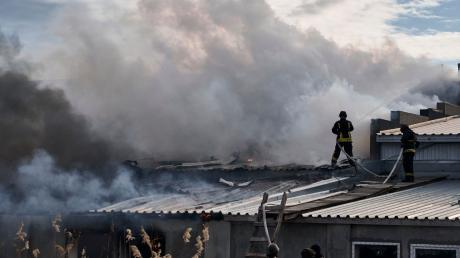 Feuerwehrleute des staatlichen ukrainischen Katastrophenschutzes löschen ein Feuer, das nach Beschuss eines Industriegebiets in Cherson ausgebrochen ist.