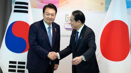Japans Ministerpräsident Fumio Kishida und der südkoreanische Präsident Yoon Suk Yeol schütteln sich die Hände während ihres bilateralen Treffens anlässlich des G7-Gipfels.