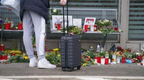 Eine Reisende schaut sich die Blumen, Kerzen und verschiedene Bilder im Wartehäuschen am Bahnhof zum Gedenken an die Opfer der Messerattacke an.