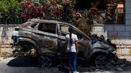Ein Mädchen steht in Turmus Aya im Westjordanland neben einem Auto, das infolge eines Brandanschlags durch jüdische Siedler zerstört worden ist.