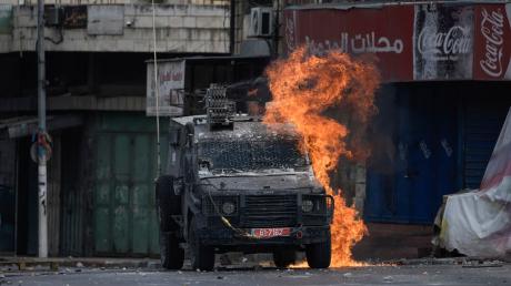 Ein von einem palästinensischen Demonstranten geworfener Molotowcocktail explodiert auf einem israelischen gepanzerten Fahrzeug in Nablus.