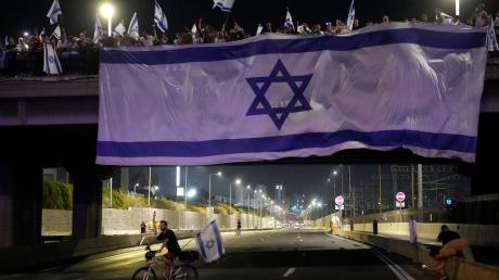 Demonstranten haben bei ihren Protesten eine riesige Nationalfahne an einer Autobahnüberführung in Tel Aviv aufgehängt.
