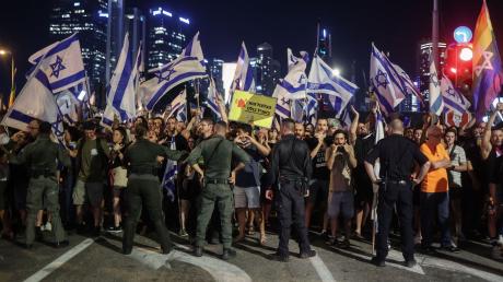 Polizisten stehen vor Demonstranten während eines Protests gegen die israelische Regierung.