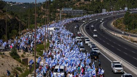 Tausende israelische Demonstranten marschieren entlang einer Autobahn, um gegen die geplante Justizreform der Regierung zu protestieren.