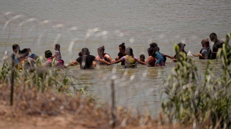 Migranten überqueren Hand in Hand den Fluss Rio Grande zwischen Mexiko und den USA.
