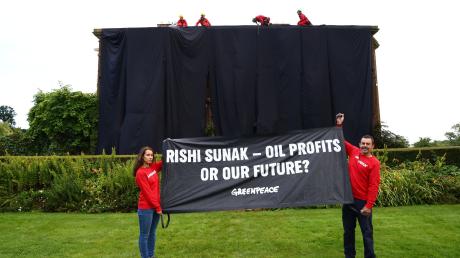 Greenpeace-Aktivisten mit einem Banner vor dem verhüllten Haus des britischen Premiers Rishi Sunak.