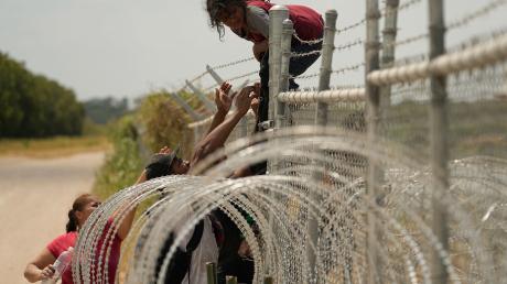 Migranten, die den Rio Grande von Mexiko in die USA überquert haben, klettern in Texas über einen Zaun mit Stacheldraht.