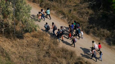 Migranten gehen im Süden von Texas über einen Feldweg, nachdem sie die Grenze zwischen den USA und Mexiko überquert haben.