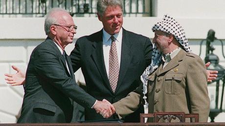 Ein Handschlag, der die Hoffnungen auf einen Frieden zwischen Israel und den Palästinensern symbolisiert: Der damalige Ministerpräsident von Israel, Izchak Rabin (l), und Jassir Arafat (r), damaliger Vorsitzender der Palästinensischen Befreiungsorganisation PLO, geben sich im Beisein von Ex-US-Präsident Bill Clinton die Hand.