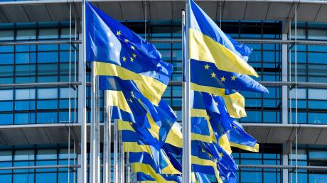 Europäische und ukrainische Flaggen wehen vor dem Europäischen Parlament in Straßburg. Die EU-Kommission erklärt die positive Empfehlung für das osteuropäische Land damit, dass die noch ausstehenden Reformen bereits auf den Weg gebracht seien.