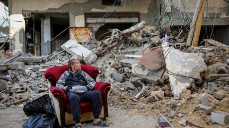 Ein palästinensischer Mann sitzt in einem Sessel vor einem zerstörten Gebäude in Gaza-Stadt.