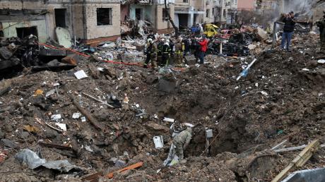 Rettungskräfte stehen neben einem Krater in der Nähe beschädigter Wohngebäude nach einem russischen Raketenangriff.